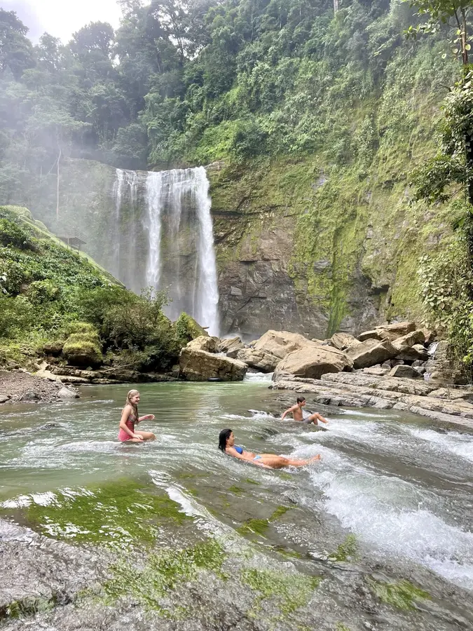 A group enjoying natural waters below a Costa Rica waterfall