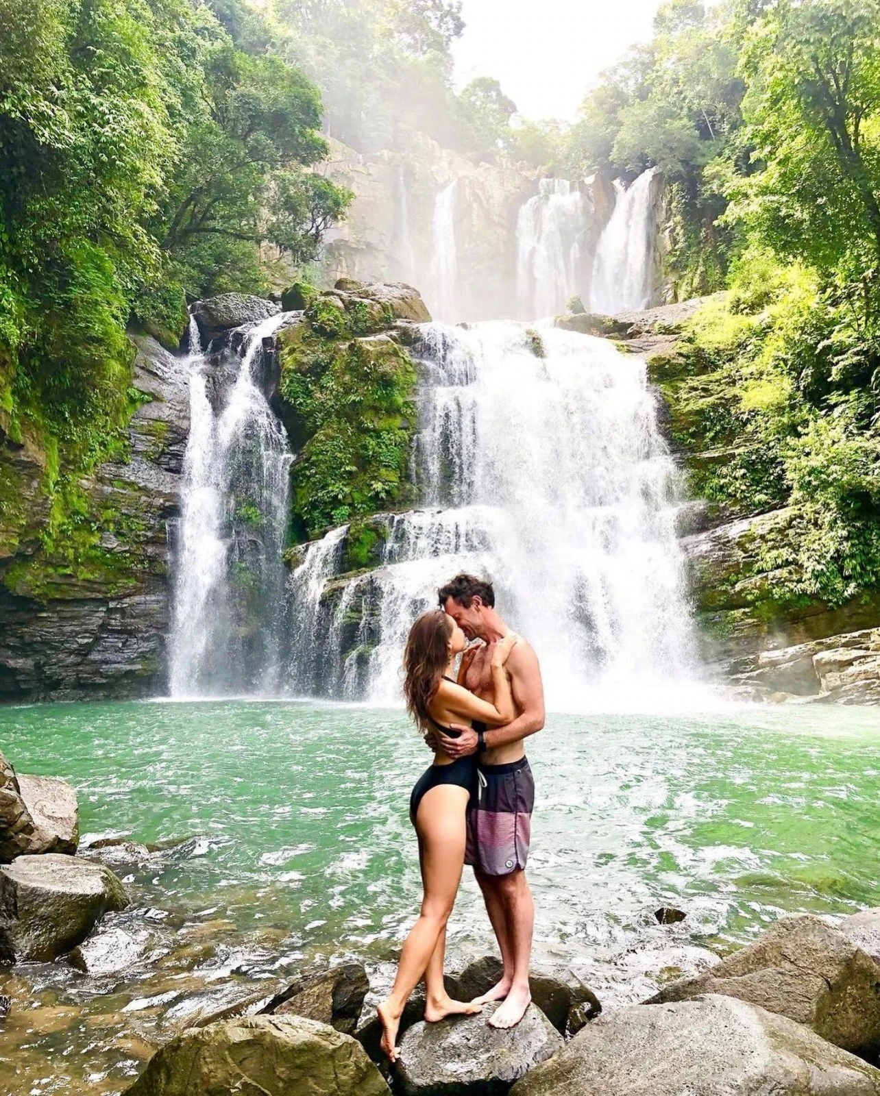 A couple embracing beneath a Costa Rican waterfall