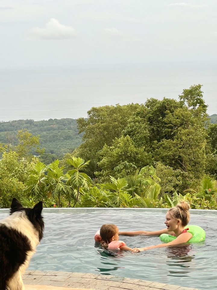 Children swimming with the dog watching beside the infinity pool